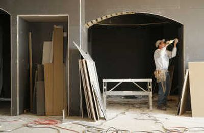 
A construction worker puts up coated sheet rock in a 5,500 square-foot green home built by Norm Schreifels in Corrales, N.M., last year. The black coating on the dry wall helps the applied natural finish adhere to the walls better. Contractors are using better building techniques and environmentally friendly materials to create what some in the industry are describing as the future of homebuilding.
 (Associated Press / The Spokesman-Review)