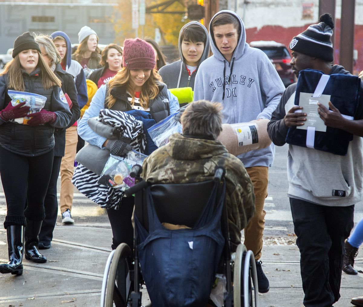 Rogers High School students, lead by Sam Wynne, second from left holding blankets, offers necessities to a fellow in a wheelchair, Monday, Nov. 6, 2017, at the House of Charity in Spokane, Wash. (Dan Pelle / The Spokesman-Review)