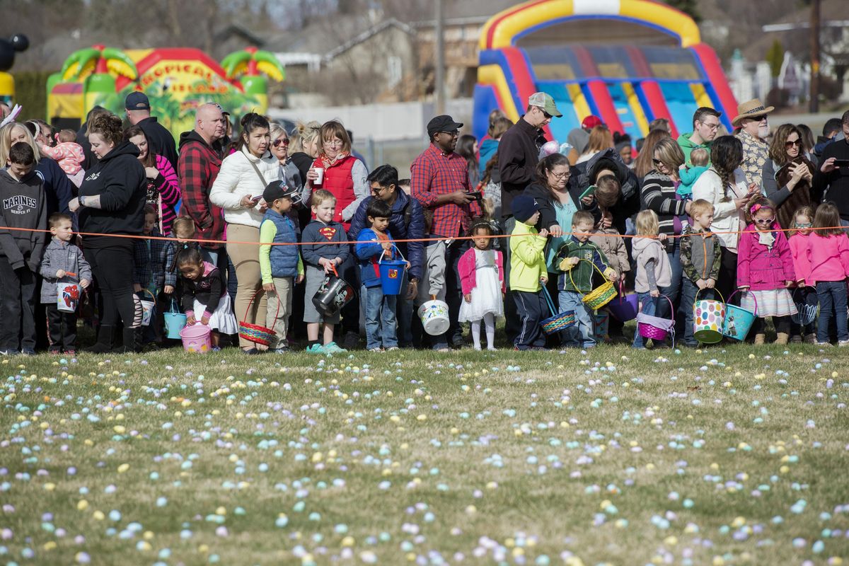 Families with young children line up at the edge of a field liberally sprinkled with plastic eggs filled with candy at One* church in Spokane Valley, Saturday, Mar. 31, 2018. The church threw a large celebration with the egg hunt, bouncing castles, face painting and other activities. (Jesse Tinsley / The Spokesman-Review)