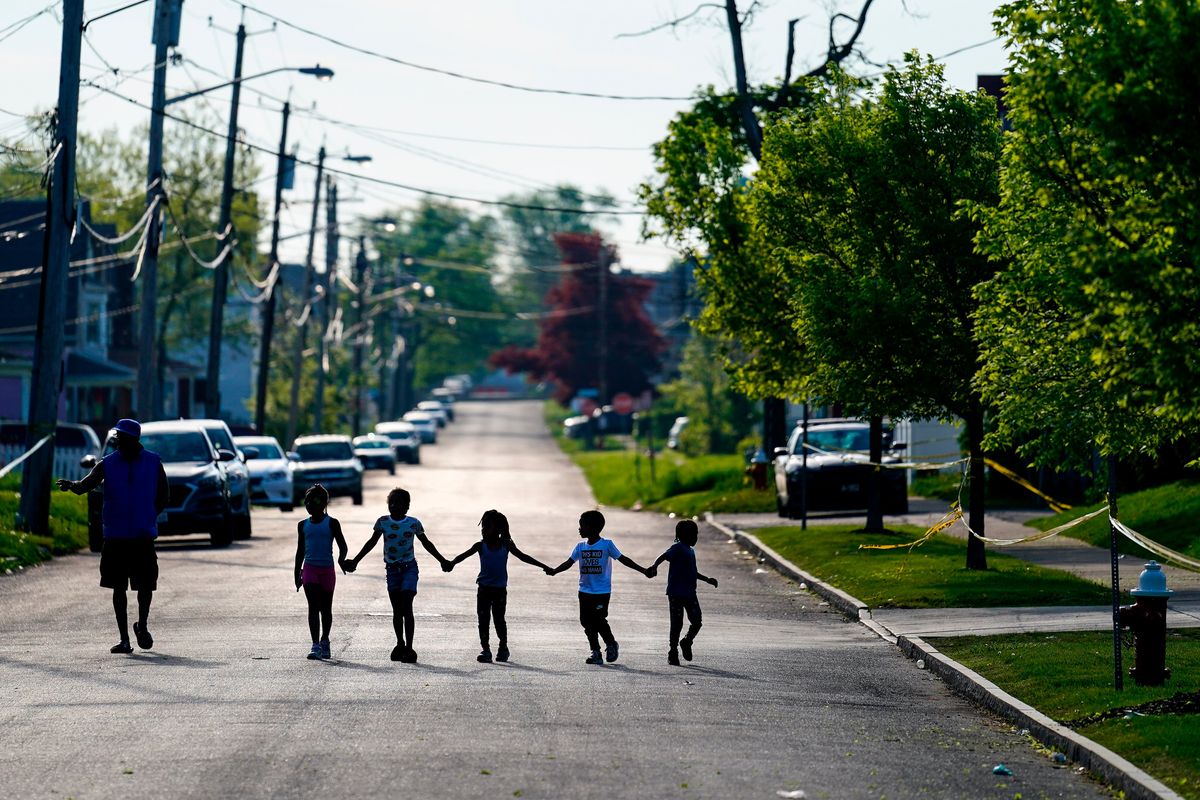FILE - Children walk hand in hand in a street near the scene of a shooting at a supermarket in Buffalo, N.Y., Sunday, May 15, 2022. Long before an 18-year-old avowed white supremacist inflicted terror at a Buffalo supermarket, the city
