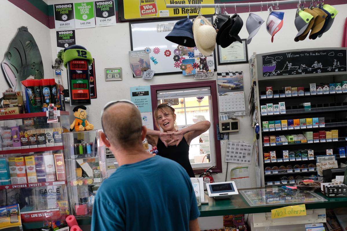 Corrine Rogers, owner of the Nine Mile Store, laughs with local patron Troy Johnson, as they share community news about the Autumn Lane fire and road closures Tuesday in Nine Mile Falls. Rogers has kept her store and gas station open amid the fire to serve the community.  (Tyler Tjomsland/The Spokesman-Review)