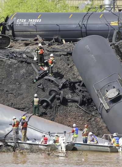 Workers remove damaged tanker cars along the tracks where several CSX tanker cars carrying crude oil derailed and caught fire along the James River near downtown Lynchburg, Va., last week. (Associated Press)