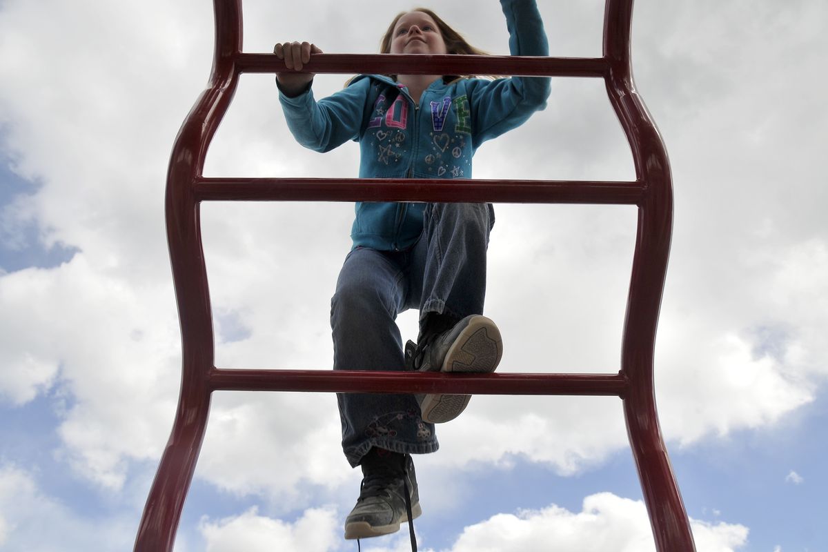 Leah Tarbert, 10, climbs up part of the new playground equipment at Seth Woodard Elementary School in Spokane Valley on Monday. The new equipment – an instant hit with the kids – includes slides, monkey bars, poles and more. (Jesse Tinsley)