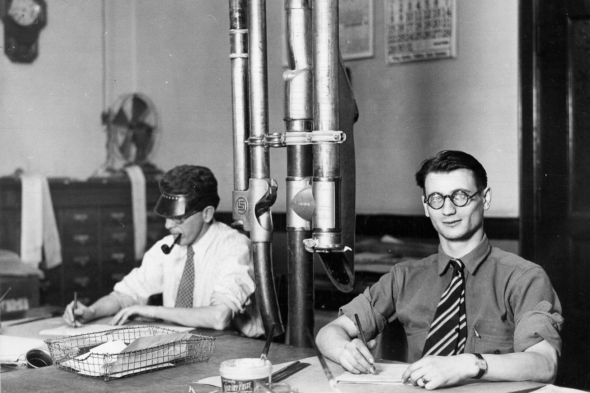 The Spokesman-Review newsroom copy editors J. H. McKechnie,  left, and Maurice Amiot in 1928, edit the day’s news stories before sending them to the typesetter via the pneumatic tubes, center. (Archives / SR)