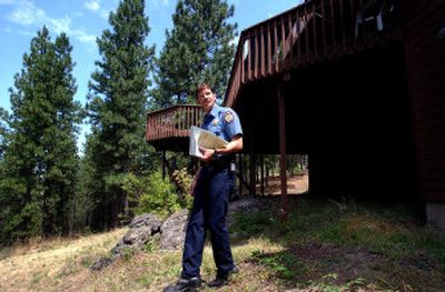 
Spokane Valley Fire Department Capt. Jon Sprague walks around the perimeter of Richard Burd's home on Green Ridge in Liberty Lake on Thursday. Decks are often a problem area for fires, however this deck is cleared of any brush and there is water access under it. If the fire gets in the crowns of the trees it could possibly jump to the deck. 
 (Liz Kishimoto / The Spokesman-Review)