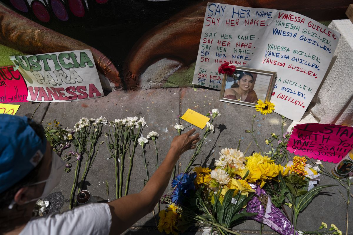 FILE - Frida Larios places flowers near of photograph of slain Army Spc. Vanessa Guillen at the base of a mural of Guillen on 14th Street NW in Washington, July 13, 2020. Guillen was killed by a soldier, who her family says sexually harassed her, and who killed himself as police sought to arrest him. (Carolyn Kaster)