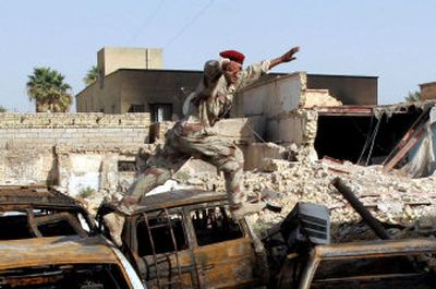 
An Iraqi soldier on Saturday jumps over cars that were burned outside a police station Friday in Amarah during fighting that killed at least 25.
 (Associated Press / The Spokesman-Review)
