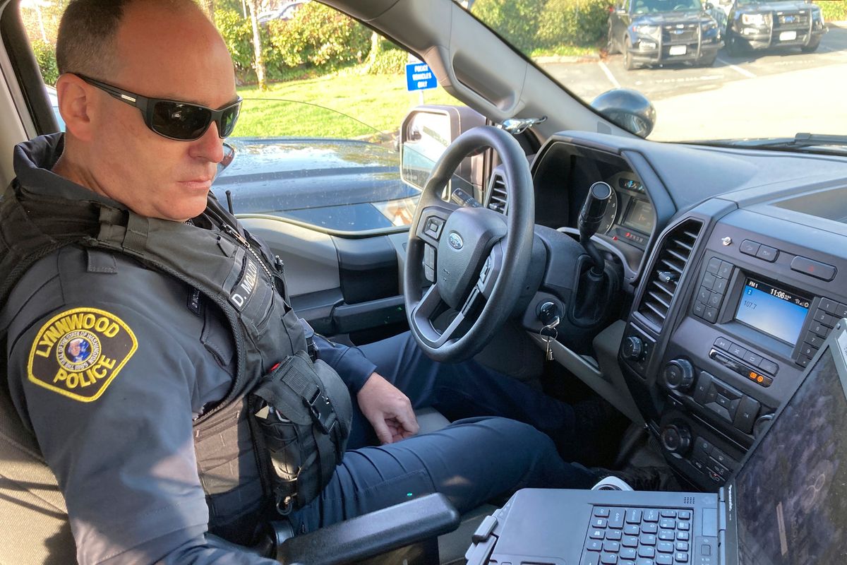 Lynnwood police Officer Denis Molloy works in his vehicle Nov. 17 in Lynnwood, Wash. Molloy, of the Lynnwood Police Department’s community health and safety section, says that navigating recent police reforms in Washington state has been challenging.  (Gene Johnson)