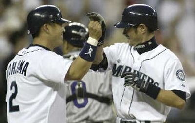 
Kenji Johjima, left, meets Ichiro Suzuki at home plate after his Seattle teammate hit a two-run home run to right field off David Cortes in the sixth.
 (Associated Press / The Spokesman-Review)