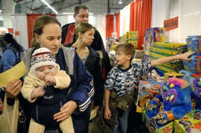 
Sarah Vasquez and her 3-month-old son, Mateo, search for gifts in the toy area on the opening day of the Christmas Bureau on Saturday at the fairgrounds. Brain Godwin, right, points out  a box of K'Nex to Sean McGee and Amber Ramm. 
 (Dan Pelle / The Spokesman-Review)