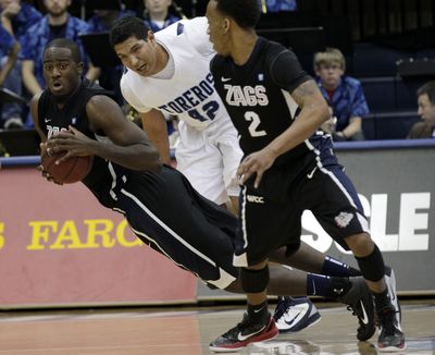Gonzaga's Sam Dower, left, picks up a loose ball as San Diego's Chris Gabriel, center, and Gonzaga's Marquise Carter, right, look on in the first half of their NCAA college basketball game on Saturday, Feb. 26, 2011, in San Diego. (Gregory Bull / Associated Press)