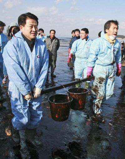 
Presidential candidate Chung Dong-young, left, and a party member carry away crude oil removed from Mallipo beach. Associated Press
 (Associated Press / The Spokesman-Review)