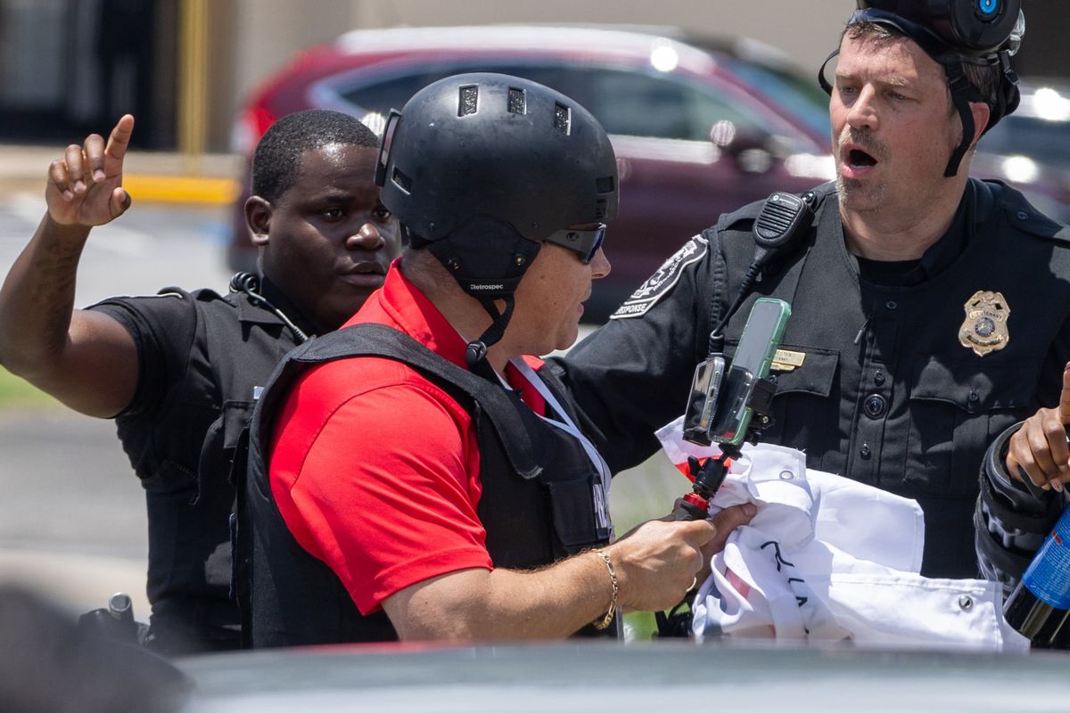 Police tell Spanish-language reporter Mario Guevara to move back during a protest on ICE raids and deportation arrests on Chamblee Tucker Road in Atlanta on Saturday. (Arvin Temkar/Atlanta Journal-Constitution)