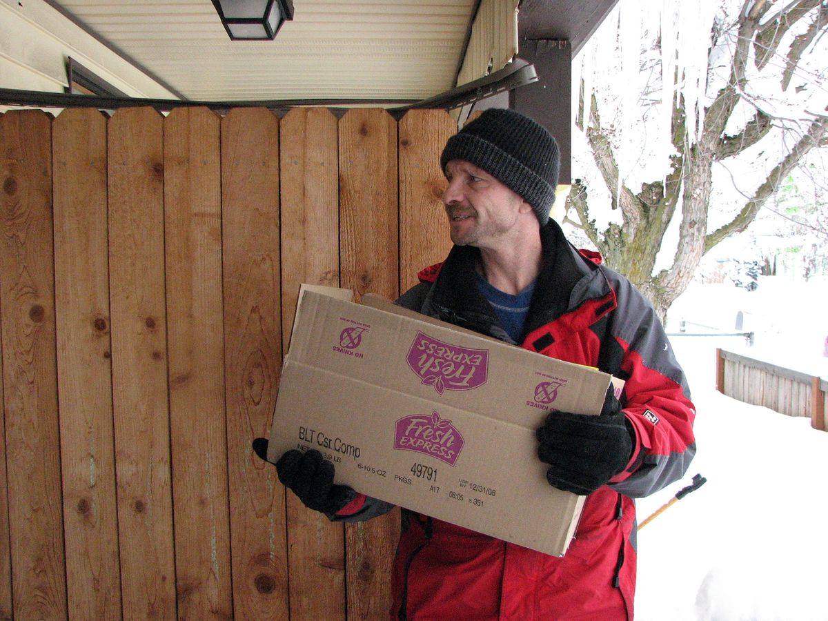 John Jones, from Light House of Hope,  holds a box  of food being delivered to a small house on West Broadway Avenue on Christmas Eve.  (Pia Hallenberg / The Spokesman-Review)