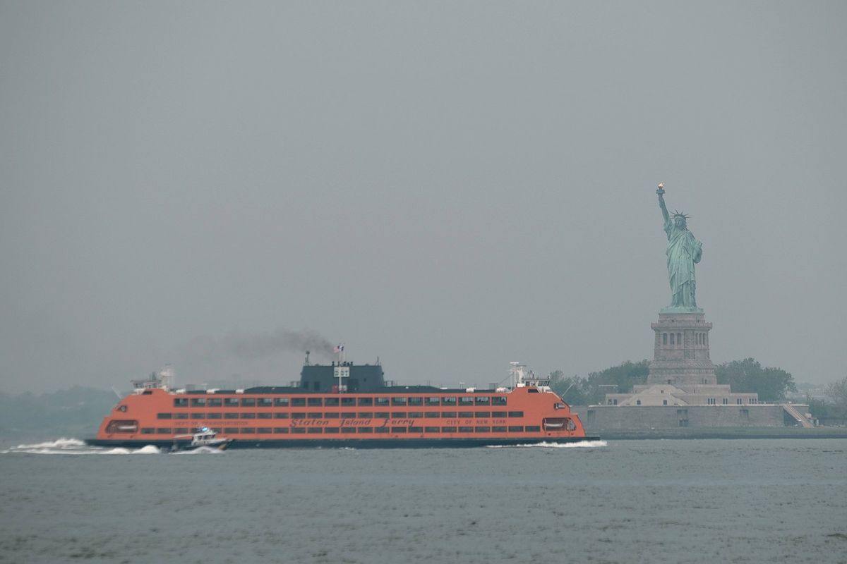 The Staten Island Ferry moves past the Statue of Liberty on a hazy morning resulting from Canadian wildfires on June 6 in New York City.  (Tribune News Service)