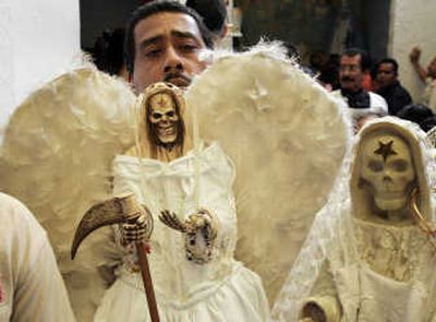 
A man holds a skeletal figure representing Santa Muerte, or Death Saint, in Mexico City on Sunday.Associated Press photos
 (Associated Press photos / The Spokesman-Review)