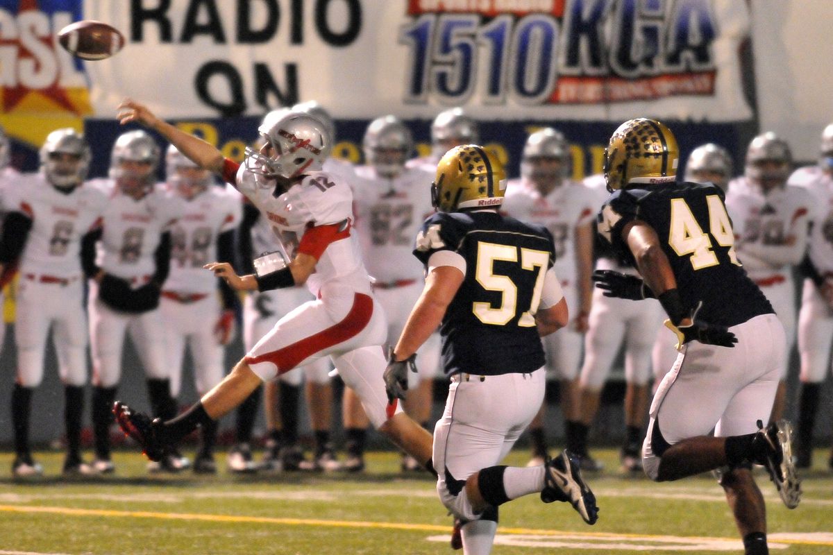 Ferris quarterback Christian Olson, left, unloads the ball as Mead’s Zach Nay (57) and Langston Ward close in. (Jesse Tinsley)