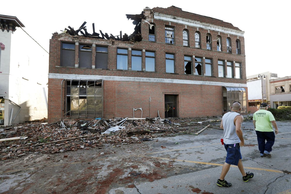 Local residents walk past a tornado damaged building on Main Street on Thursday, July 19, 2018, in Marshalltown, Iowa. Several buildings were damaged by a tornado in the main business district in town including the historic courthouse. (Charlie Neibergall / AP)