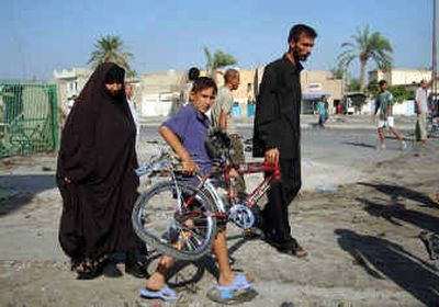 
A boy picks up the damaged bicycle of his dead brother after two car bombs and a roadside bomb went off in succession in the Al-Amel neighborhood of Baghdad on Thursday. At least 41 people were killed, most of them children, and over 200 were wounded.
 (Associated Press / The Spokesman-Review)