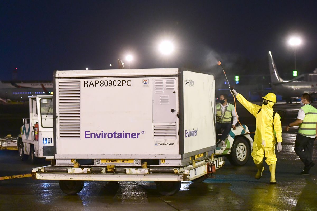 Workers spray disinfectant on boxes containing Chinese-made coronavirus vaccine Dec. 7 at a facility in Bandung, West Java, Indonesia. (HOGP/Associated Press)