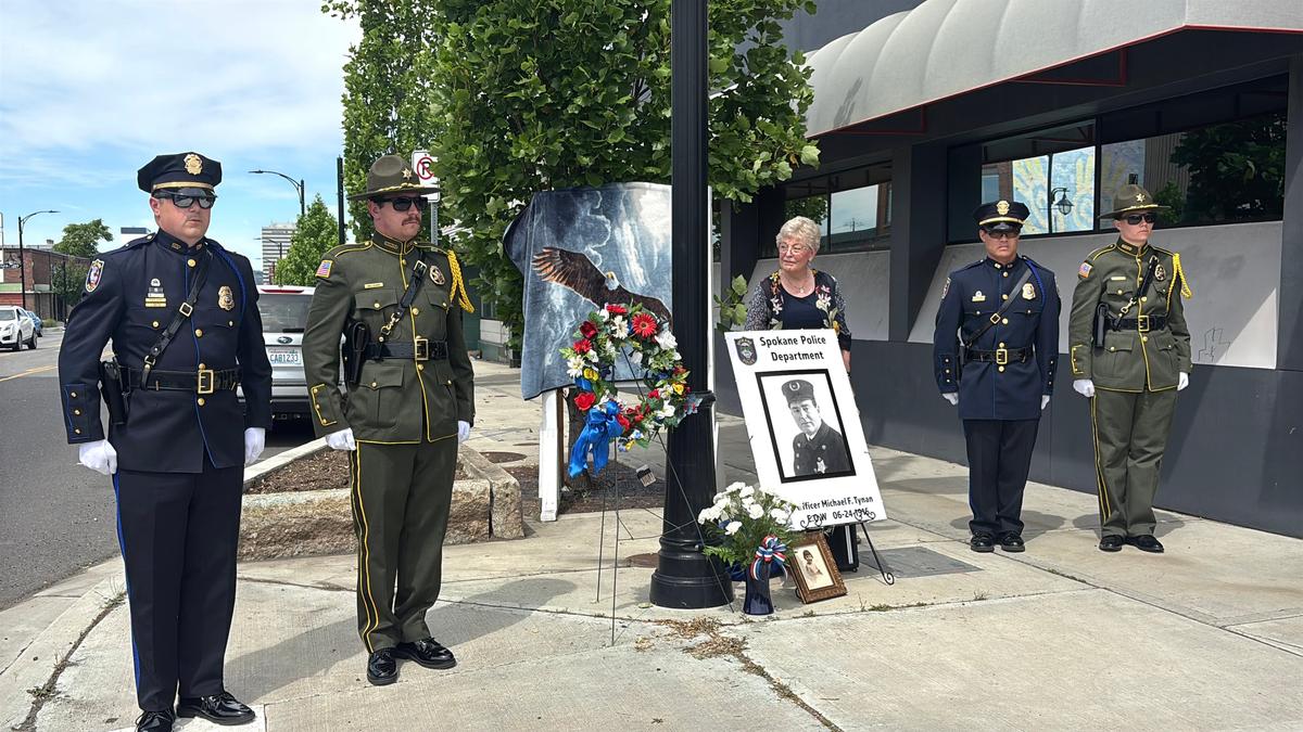As law enforcement representatives stand guard, Sue Walker, center, of the Spokane Regional Law Enforcement Museum, speaks at the placement of a plaque to commemorate the death of Spokane Police Department officer Michael F. Tynan at the corner of Grant Street and Sprague Avenue. Officer Tynan died in 1916. (Julia Pentasuglio/THE SPOKESMAN-REVIEW)