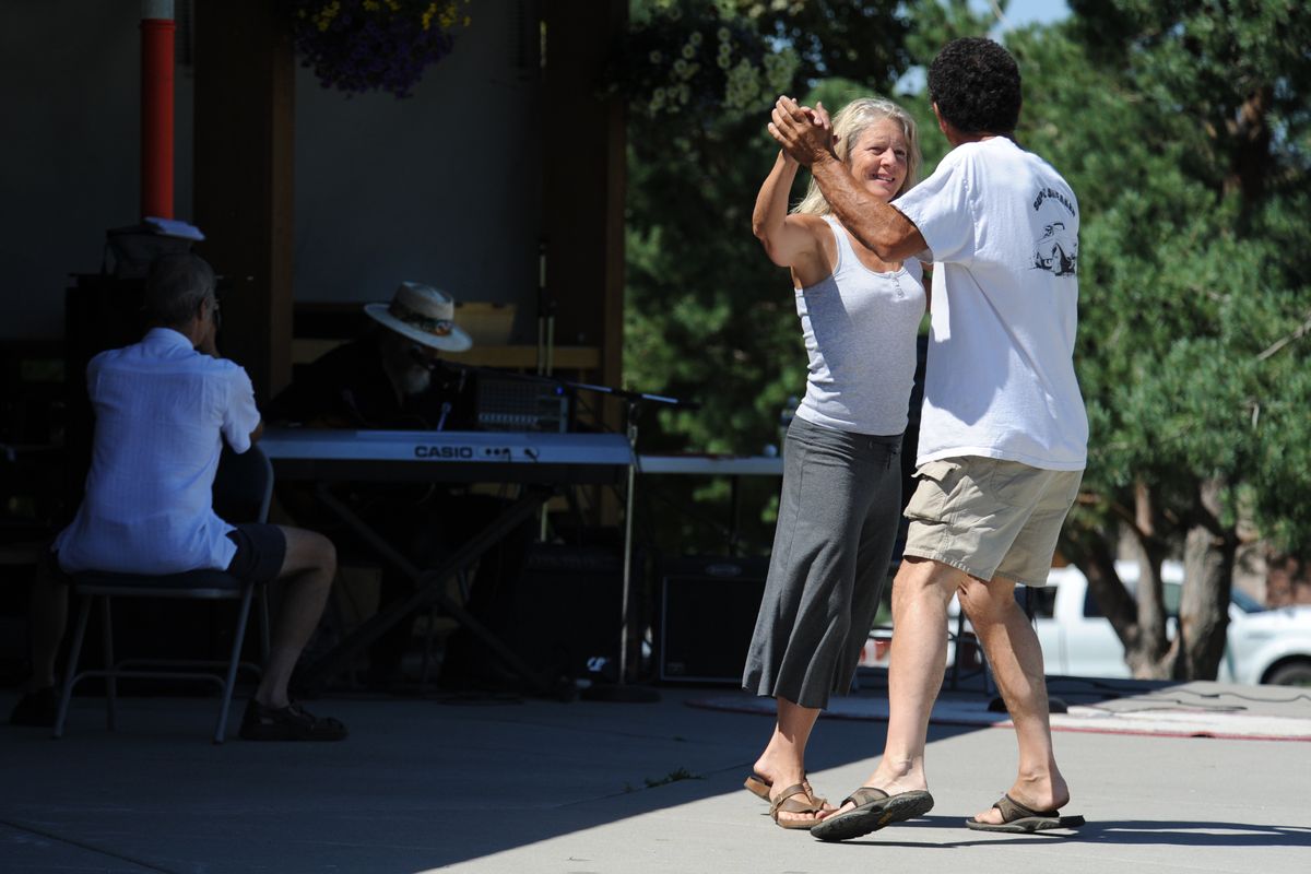 Curt Hurley and Jeanette Sheahan dance as entertainer Al Chidester (wearing a hat) sits in the shade and sings a country song on Saturday at Liberty Lake Days, a community festival featuring classic cars, food and an art show. (PHOTOS BY JESSE TINSLEY)