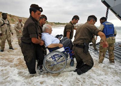 
Lebanese police officers carry an elderly American citizen on a wheelchair to the USS Nashville's landing craft as it evacuates stranded Americans from the beach north of Beirut on Thursday. 
 (The Spokesman-Review)
