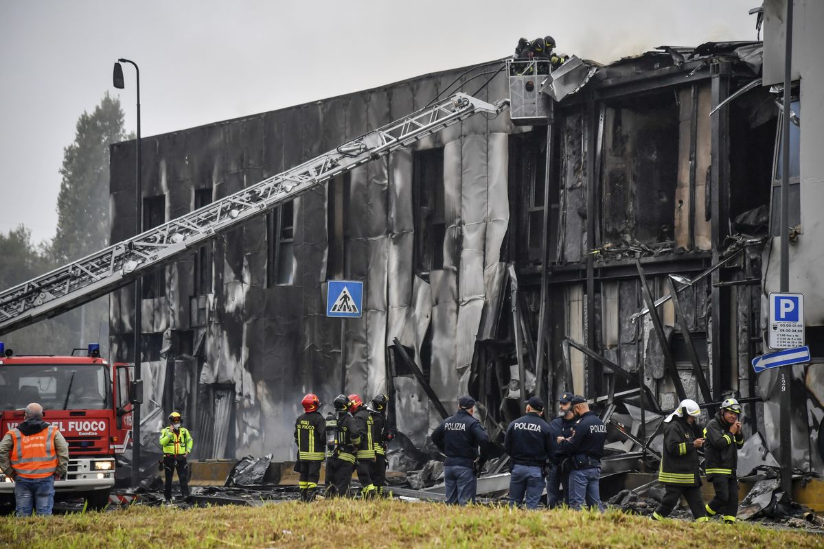 Firefighters work on the site of a plane crash, in San Donato Milanese suburb of Milan, Italy, Sunday, Oct. 3, 2021. According to media reports, a small plane carrying five passengers and the pilot crashed into an apparently vacant office building in a Milan suburb. Their fates were not immediately known.  (Claudio Furlan)