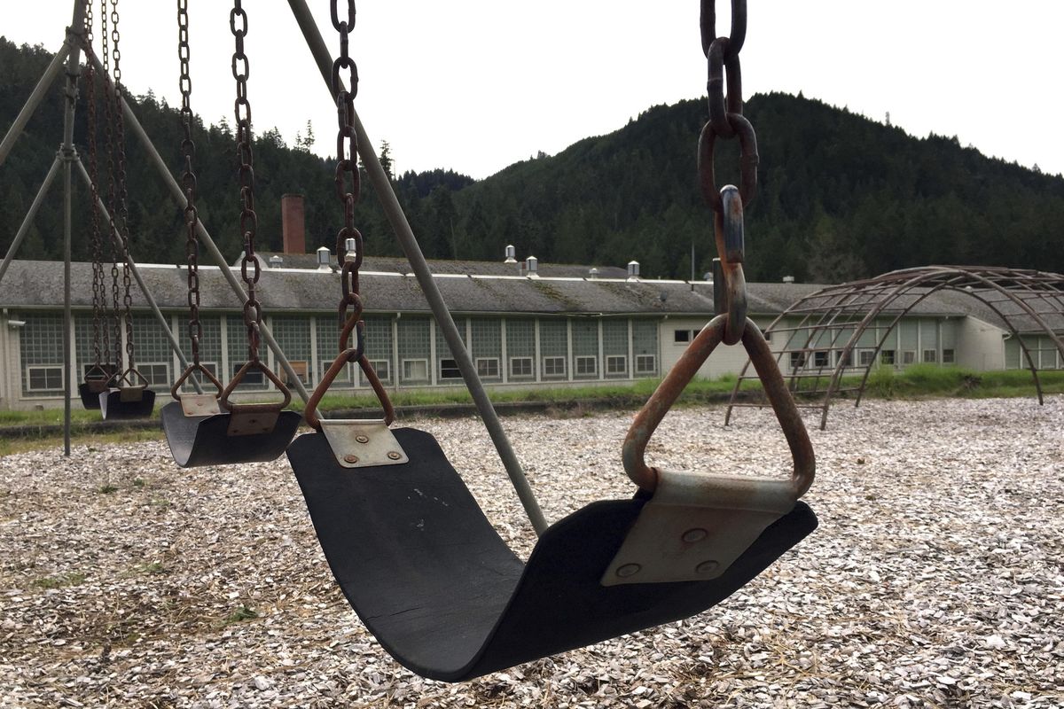 In this April 5, 2017, photo, the abandoned Tiller Elementary School playground is seen in the foreground with the school in the background in downtown Tiller, Ore. (Gillian Flaccus / Associated Press)