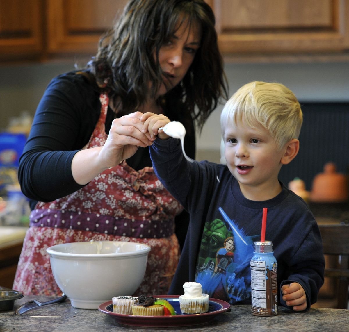Julie Grant and her son, Carson, 4, drip melted almond bark onto treats to create healthier Halloween fun snacks in their Eagle Ridge home. (Dan Pelle / The Spokesman-Review)