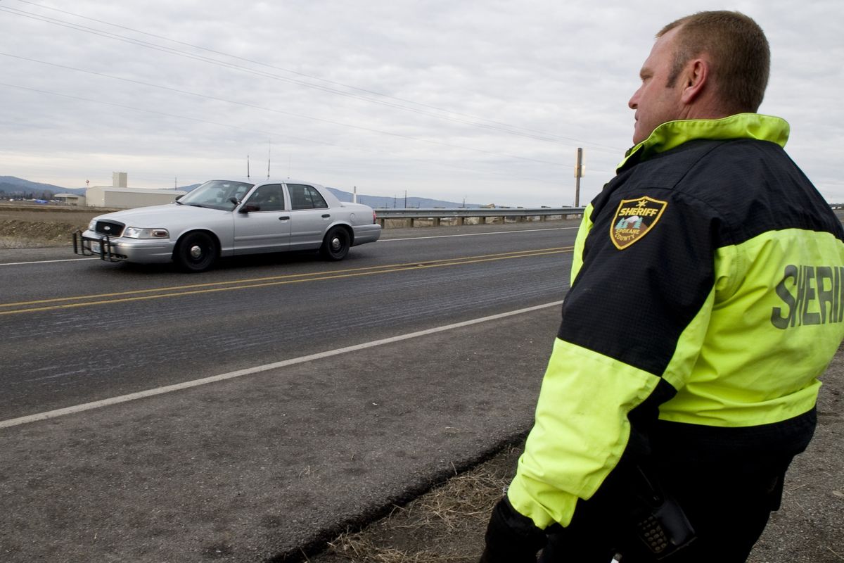 Sheriff’s Deputy Craig Chamberlin monitors how well a test car brakes after an  application of liquid de-icer near the intersection of  Wellesley and Trent avenues Jan. 29, during the reconstruction of an accident that  injured two East Valley High students Dec. 29.colinm@spokesman.com (Colin Mulvany)