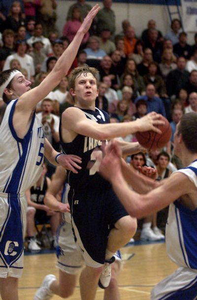 
Lake City's Cory Kreighbaum, center, is fouled by Coeur d'Alene's Austin Heleker, left, in the fourth quarter Friday night. 
 (Tom Davenport / / The Spokesman-Review)