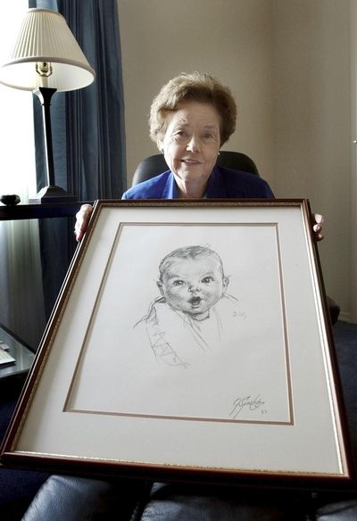 In this 2004 file photo, Ann Taylor Cook poses at her Tampa, Fla., home with a copy of her photo that is used on all Gerber baby food products. Gerber says Cook turned 90 on Sunday. (Chris O'Meara / Associated Press)