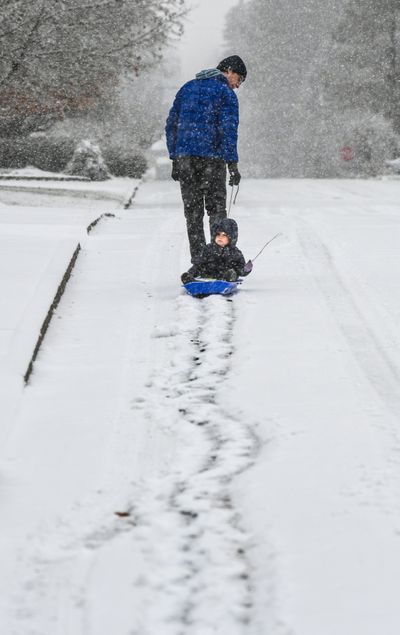 Tim Greenup, and his daughter, Norma, 2, make trails in the snow as the make their way along 35th Avenue during a Friday morning snow shower, Dec. 11, 2020, in Spokane. The pair had travel five blocks around their neighborhood and even stopped at a Little Free Library to select a book for Norma. (DAN PELLE/THE SPOKESMAN-REVIEW)