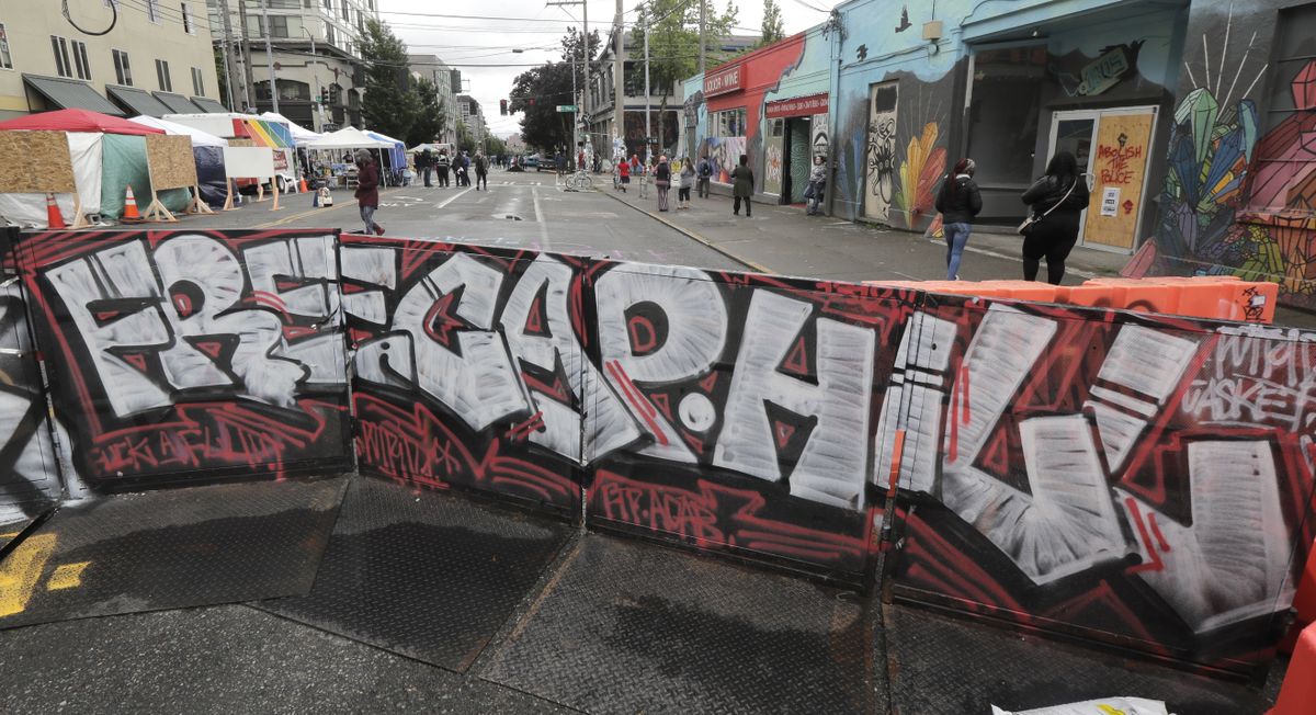 A sign at an entrance to what has been named the Capitol Hill Occupied Protest zone in Seattle reads "Free Cap Hill," Monday, June 15, 2020. Protesters have taken over several blocks near downtown Seattle after officers withdrew from a police station in the area following violent confrontations.  (Ted S. Warren)
