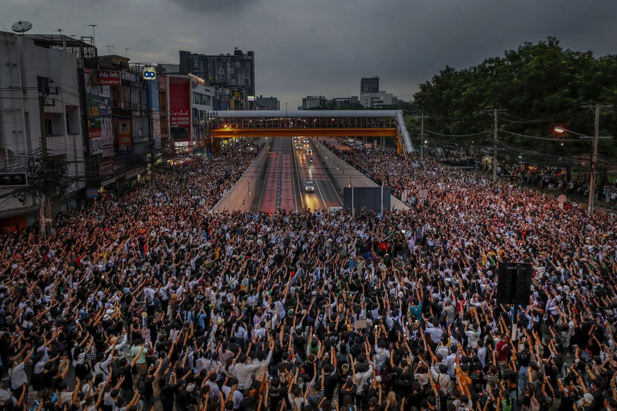 Pro-democracy activists flash three-fingered salutes during a demonstration at Kaset intersection, suburbs of Bangkok, Thailand, Monday, Oct. 19, 2020. Thai authorities worked Monday to stem a growing tide of protests calling for the prime minister to resign by threatening to censor news coverage, raiding a publishing house and attempting to block the Telegram messaging app used by demonstrators.  (Sakchai Lalit)
