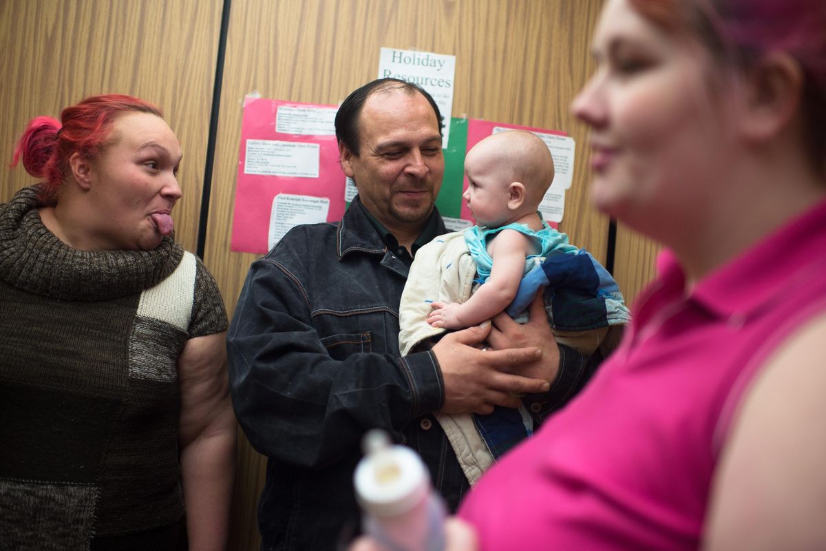 Cassandra Moffitt, left, makes a face at infant Zamariah, who is held by her father Anthony Whitehead, with her mother, Tiffany Link in an elevator to their living quarters provided by Rising Strong on Friday, Dec. 15, 2017, in Spokane, Wash. Moffitt, Whitehead and Link are participants in the year-long Rising Strong program, which gives parents who might otherwise lose their kids to CPS a chance to get clean from drugs and learn parenting skills. (Tyler Tjomsland / The Spokesman-Review)