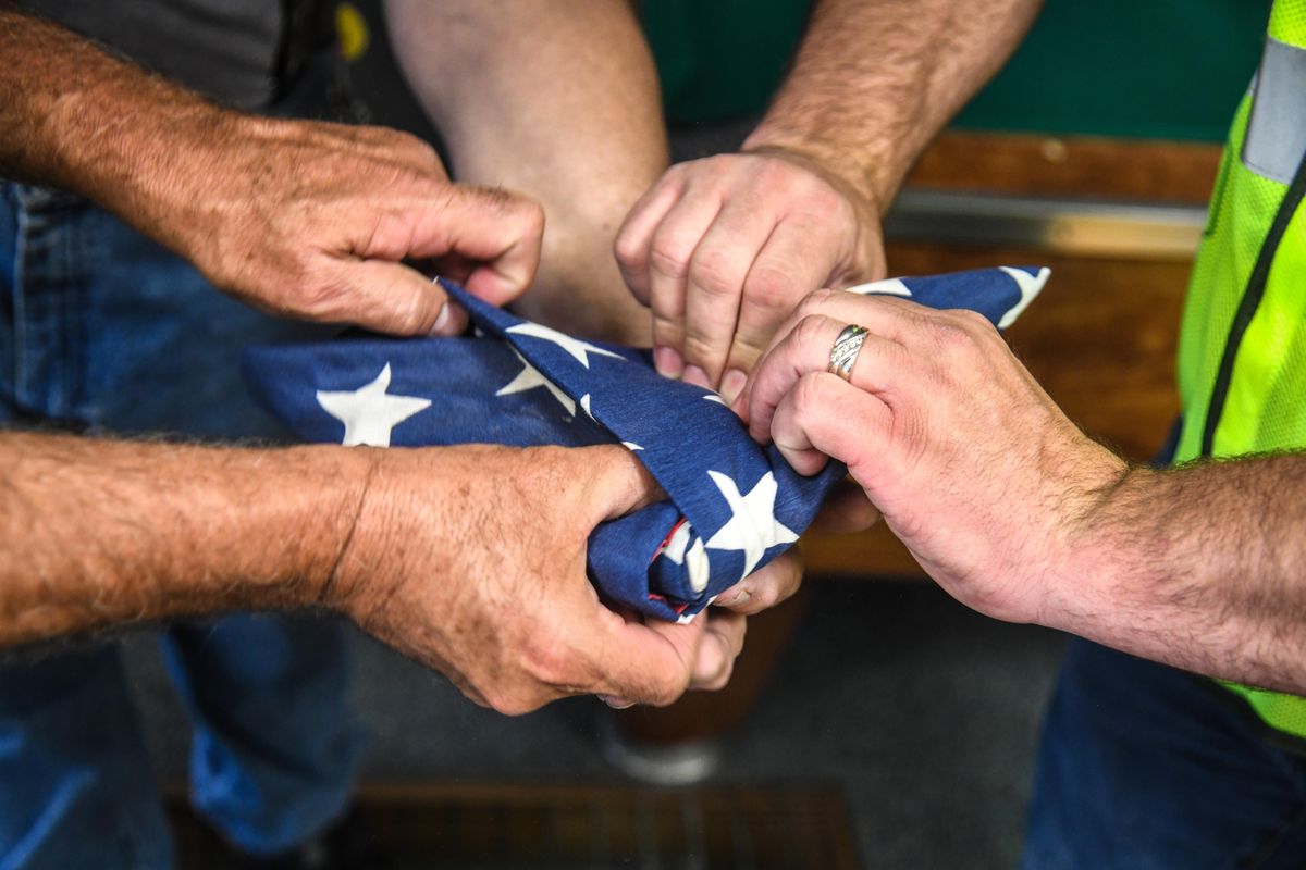 The hands of Tom Ypung and Randy Colegrove of Waste Management SMaRT Center and Sandy Judge, VFW Post 51 Commander, complete the folding of an American flag, Thursday, June 7, 2018.  the flag was pulled from the SMaRT Cetner pre-sort line and given to the VFW for proper disposal.    Dan Pelle/THE SPOKESMAN-REVIEW (Dan Pelle / The Spokesman-Review)