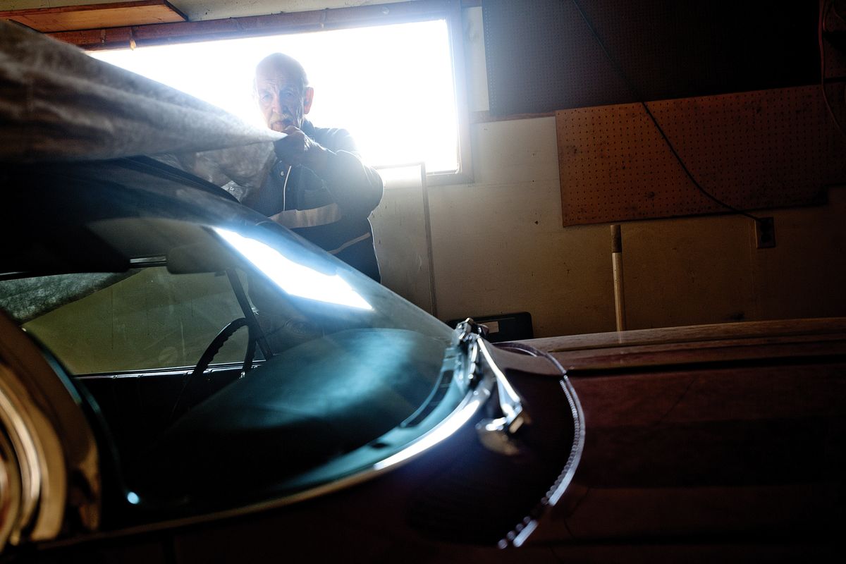 Robert Dressel pulls a protective tarp over his 1961 Oldsmobile Starfire, a car which his son repainted for him 20 years ago, Wednesday at his home in Spokane. (Tyler Tjomsland)