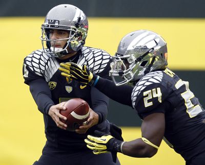 Oregon QB Marcus Mariota hands off to Kenjon Barner in a 70-14 rout of Colorado. (Associated Press)