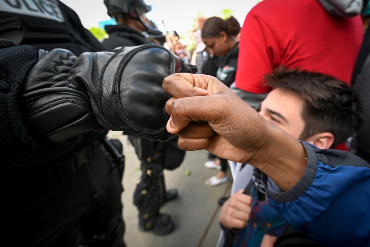 “Respect goes both ways,” said a protester named Monique who fist bumps a Spokane Police officer dressed in riot gear outside the Spokane County Courthouse. Thousands marched in Spokane on Sunday to protest George Floyd’s death, police brutality. (Colin Mulvany / The Spokesman-Review)