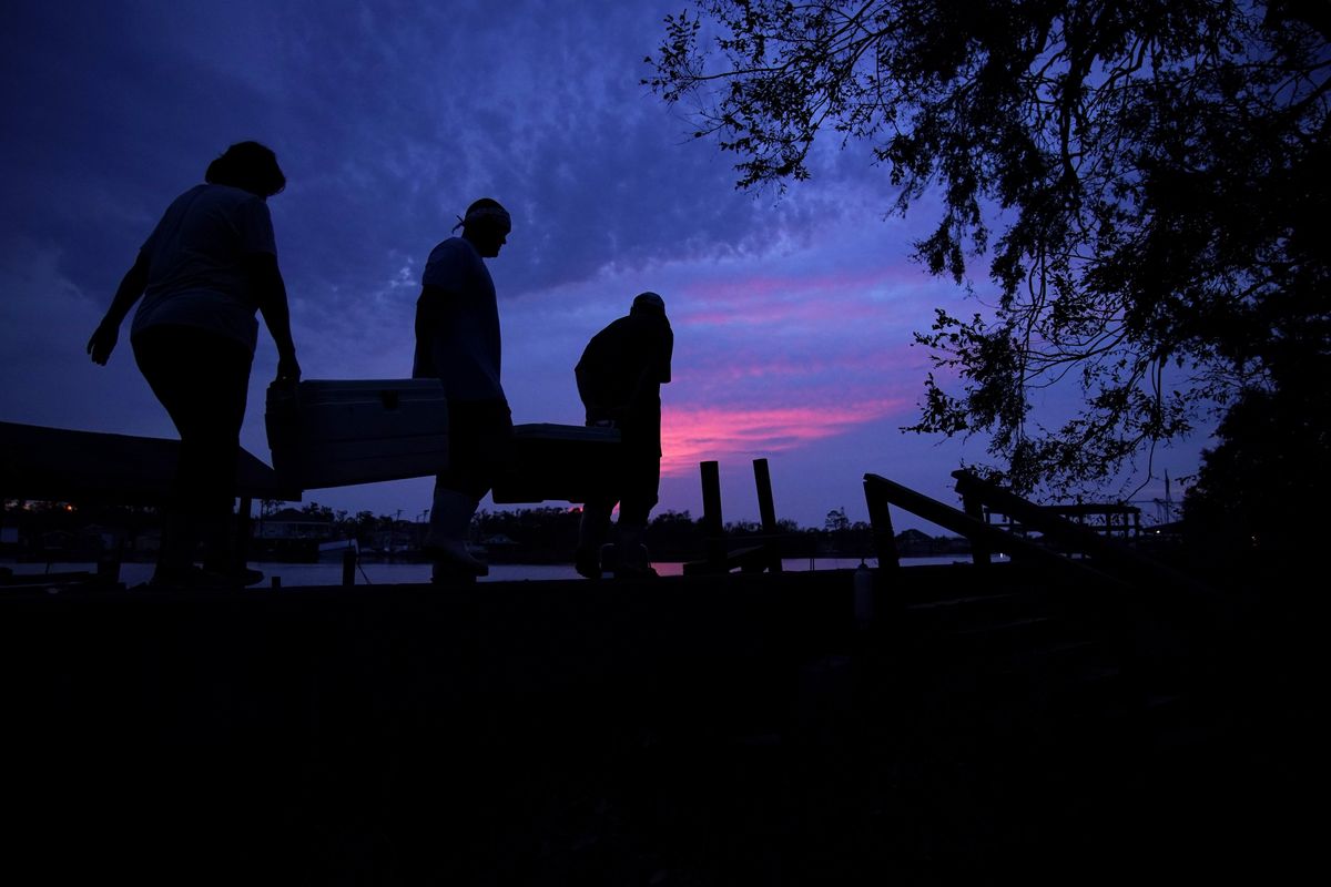 People carry supplies to their boat at dusk in the aftermath of Hurricane Ida, Wednesday, Sept. 1, 2021, in Jean Lafitte, La.  (John Locher)
