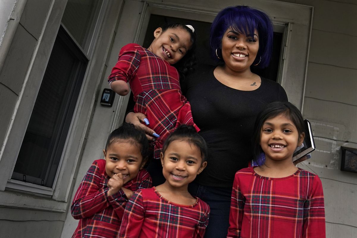 Dinora Torres, a MassBay Community College student, poses with her four daughters on the front porch of their home, Thursday, Jan. 14, 2021, in Milford, Mass. From front left are daughters Davina, Alana and Hope, with Faith in Dinora