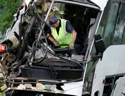 An emergency worker wrestles with the steering wheel on a charter bus that was crushed when it skidded off a highway in Sherman, Texas, early Friday.  (Associated Press / The Spokesman-Review)