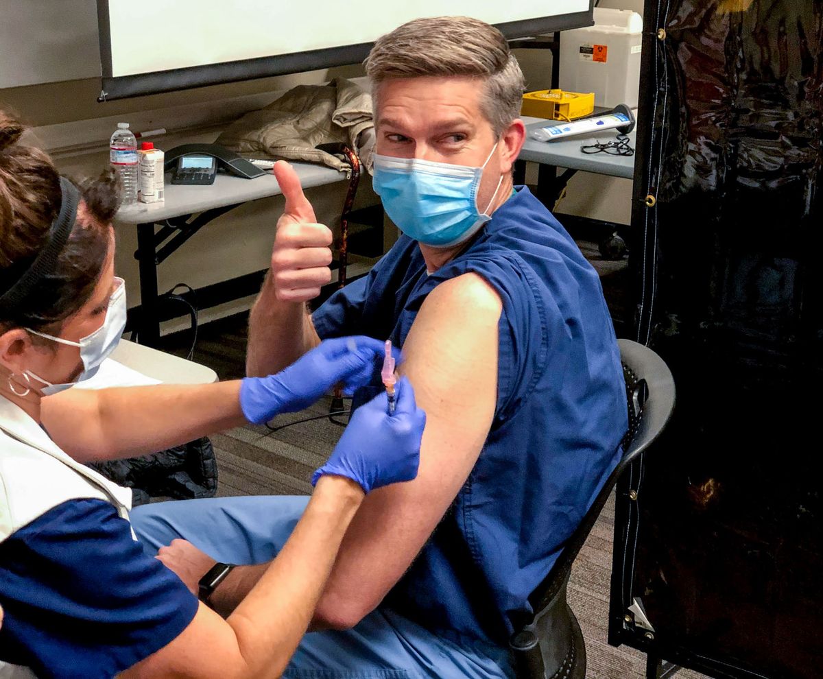 Dr. Todd Hoopman gives a thumbs-up to staff during his COVID-19 vaccination as nurse Melissa Bunch administers the vaccine Friday at Kootenai Health. Hoopman is a critical care physician, who said the vaccine marks the beginning of the eventual end to the pandemic and stressed the importance of others getting vaccinated in the coming months.  (Courtesy of Kootenai Health)