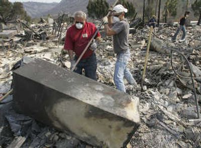 
Justin Owens, right, helps Tom Moore open a safe Thursday after returning to his home, destroyed by wildfire, in Poway, Calif. Evacuees were being allowed back into their neighborhoods.Associated Press
 (Associated Press / The Spokesman-Review)