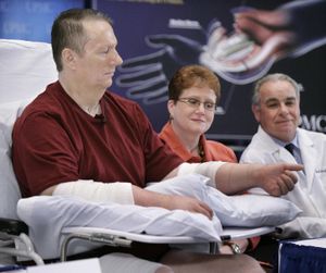 ORG XMIT: PAGP111 Double hand transplant recipient Jeff Kepner, 57, of Atlanta, Ga., left,  lifts one of his transplanted hands while wife Valerie, center, and Dr. Joseph Imbriglia look on during a news conference at the University of Pittsburgh Medical Center in Pittsburgh on Thursday, July 16, 2009. (AP Photo/Gene J. Puskar) (Gene Puskar / The Spokesman-Review)