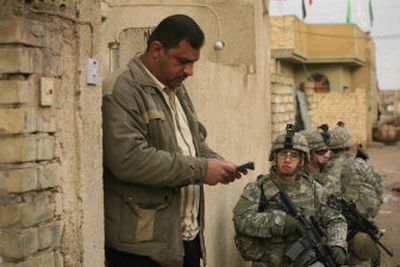 
An Iraqi reads a pamphlet asking for information on insurgents, handed to him by Sgt. John Guerra,  front, of Alpha Company, 2nd Battalion, 3rd Infantry Regiment, 3rd Stryker Brigade Combat Team, in the Shaab neighborhood of Baghdad on Friday. 
 (Associated Press / The Spokesman-Review)