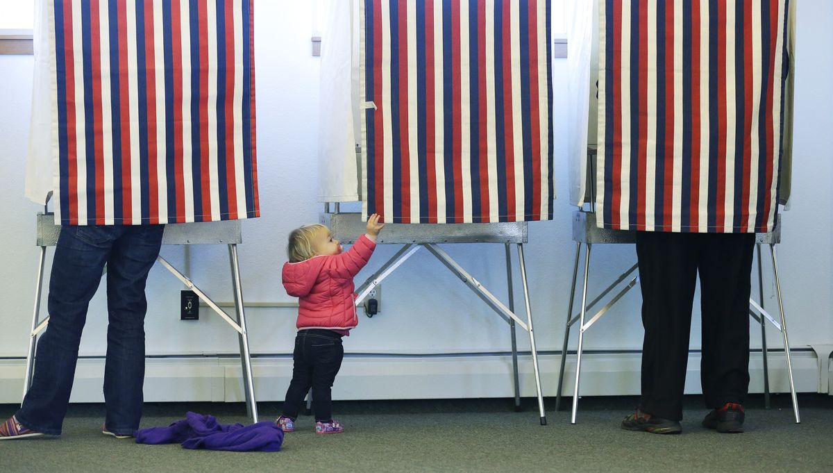 Fourteen-month-old Zoe Buck checks out an empty voting booth as her mother, Julie Buck, votes at left, Tuesday in Anchorage, Alaska. (Associated Press)