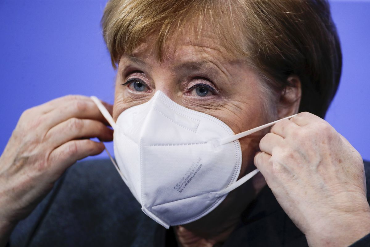 German Chancellor Angela Merkel puts on a face mask after a news conference on further coronavirus measures, at the Chancellery in Berlin, Germany, Tuesday Jan. 19, 2021.  (Hannibal Hanschke)